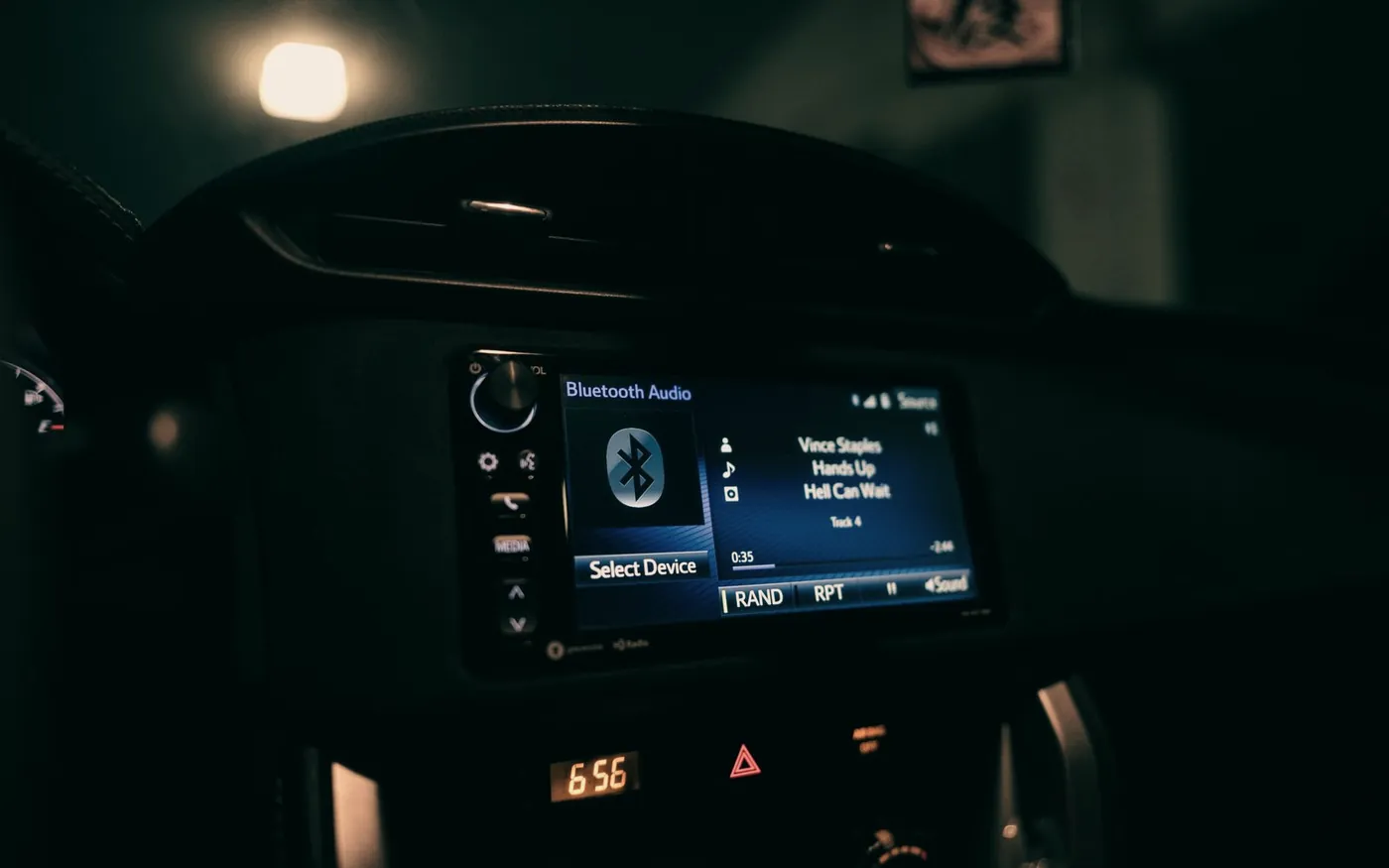 Car head unit screen lit up at night showing a Bluetooth audio source