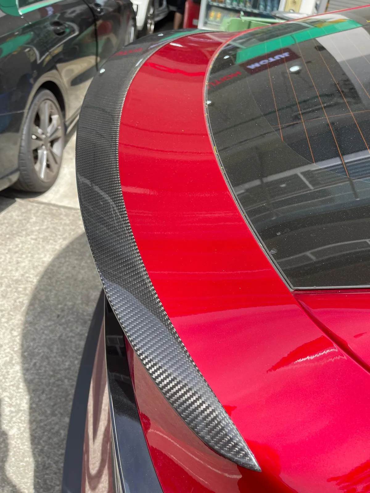 Real carbon fibre boot lip spoiler fitted to a red Tesla Model Y Juniper by Han Revolution — close-up of the weave