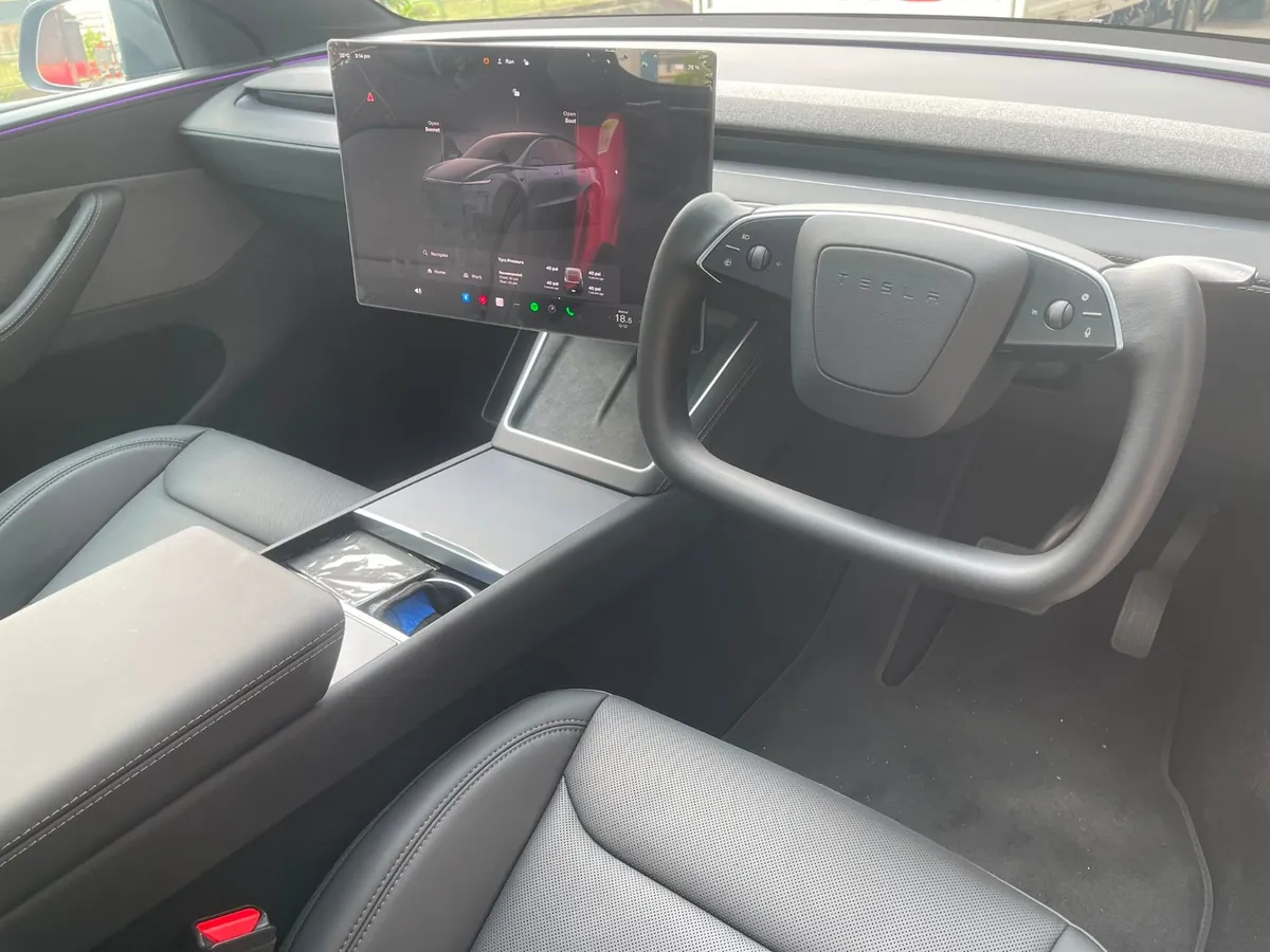 Rounded yolk steering wheel fitted to a right-hand-drive Tesla by Han Revolution, with the centre touchscreen alongside