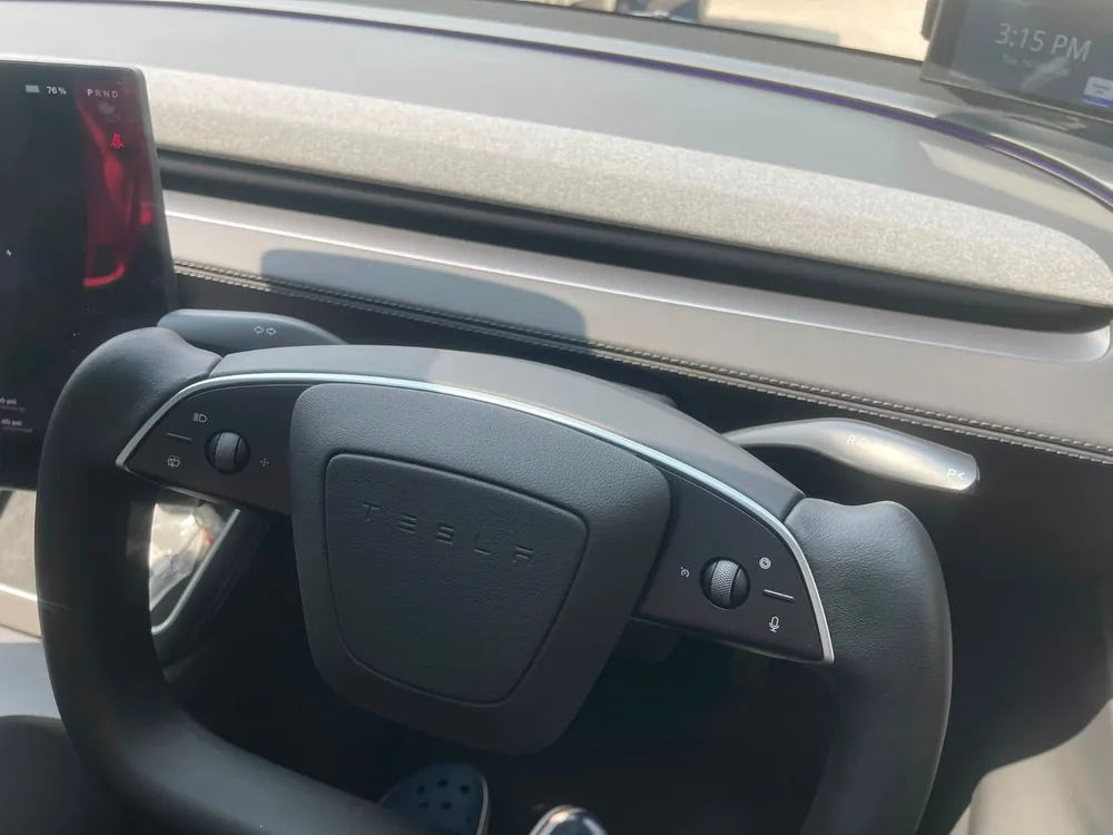 Close-up of the rounded yolk steering wheel rim and Tesla centre boss