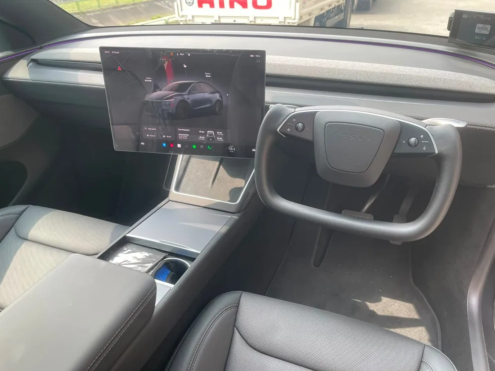 Yolk steering wheel and Tesla touchscreen viewed from the passenger side