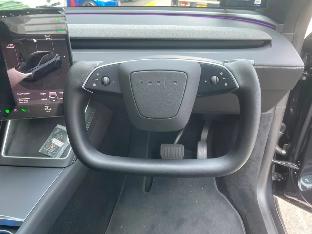 Yolk steering wheel installed in a Tesla, shown from the driver's door
