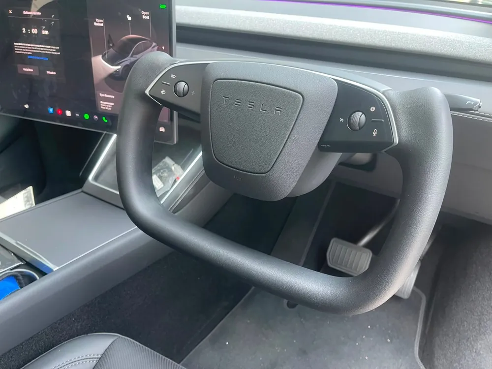Yolk steering wheel in a Tesla cabin with ambient lighting
